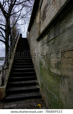 Old green moss covered steps leading to Seine River walkway with Seine river in background. 