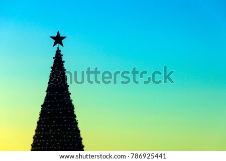 Celebratory background. Copyspace. Silhouette of an decorated Christmas tree with a five-pointed star on the vertex against the background of the morning sunny sky.
