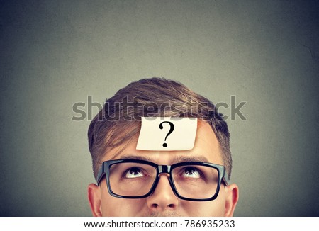 Young man wearing black glasses with question mark on forehead looking up.  Royalty-Free Stock Photo #786935233