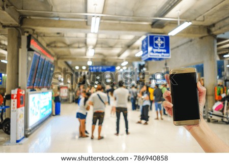 Hand holding mobile phone with airport terminal blurred crowd of Travelling people on the background, Bokeh light, Social network, internet,Traveling concept