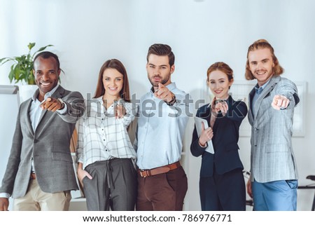 smiling multicultural businesspeople pointing on camera