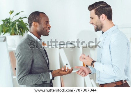 smiling african american and caucasian businessmen talking on office