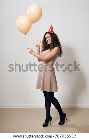 happy young woman or teen girl in brown dress with helium air balloons, holiday concept