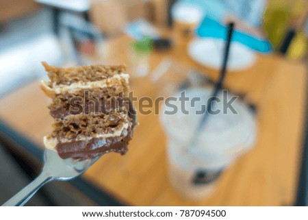 Brown cake on folk with coffee shop background