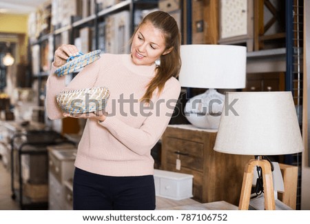 Positive woman buyer holding wicker basket in furniture store