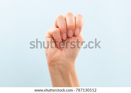 American sign language. Female hand showing letter M isolated on blue background. 