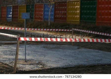 Red and white, striped protective tape protects fresh cement, repair work. Industrial artistic background