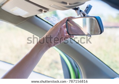Hand holding adjust rear view mirror.