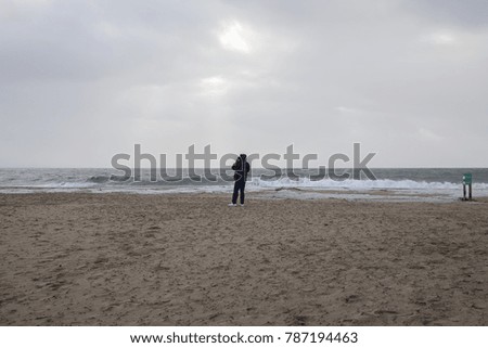 Man trying to take a picture on the beach against the wind before the storm Carmen hits the coast of La Faute Sur Mer, Vendee, France