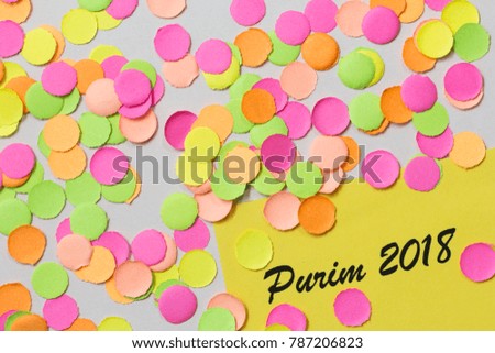 Purim celebration, Jewish tradition. Carnival party background concept, space for text. Colorful confetti spread over table. Warm colors: pink, yellow and orange.