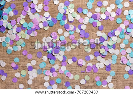 Colorful confetti spread over wooden table. Cool colors: blue, purple and aqua. Carnaval Concept.