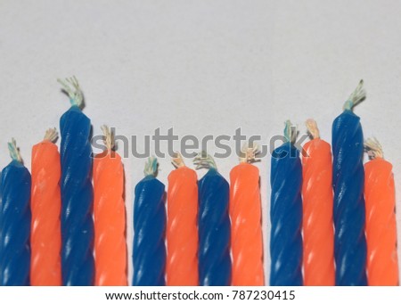 Birthday candles, blue and orange color on white background. a cylinder or block of wax or tallow with a central wick that is lit to produce light as it burns.