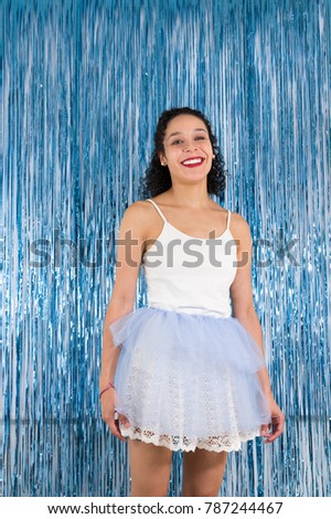 Brazilian teenager is smiling. Curly haired woman is dressed as a ballerina. Get out tutu. Colored background. Concept of celebration, Carnival, New Year's Eve, Mardi Gras.