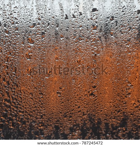 a drop of water on a windowpane. on a background - a gradient of colors from white to black through orange. sharp picture, suitable for a romantic background and mood