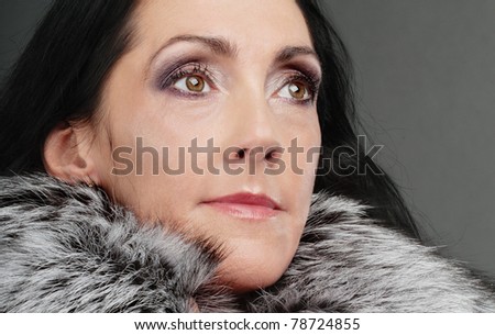 Portrait of beautiful elderly dark-haired woman in clothes with fluffy fur collar.