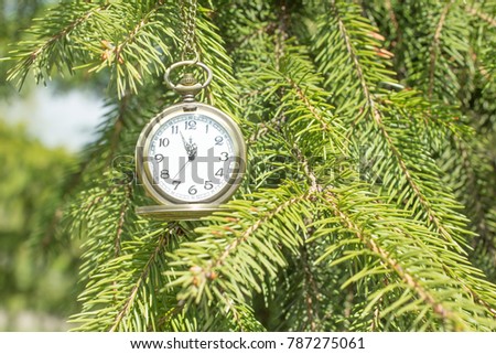 Vintage golden pocket watch on Christmas trees background, time concept. The time on the clock 11:55 PM
