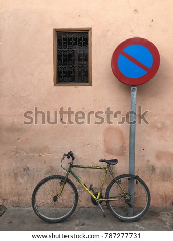 Old bicycle is parking at no parking sign by the wall with morocco style window
