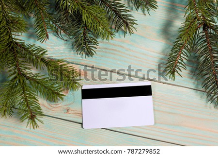 Christmas background with spruce branches and credit card on wooden board with copy space. Online shopping.