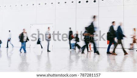 large crowd of anonymous blurred people at a trade show floor