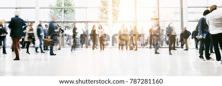 large crowd of anonymous blurred people at a trade show hall