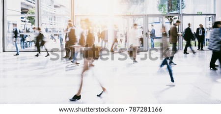 crowd of anonymous blurred people walking in a modern hall