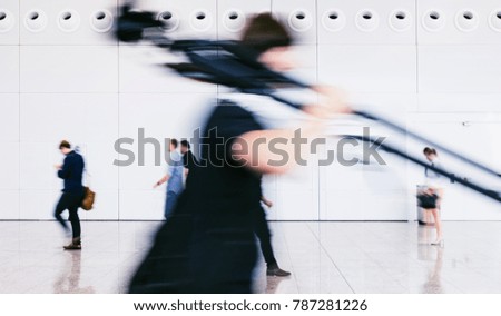 blurred photographer walking with tripod in a floor