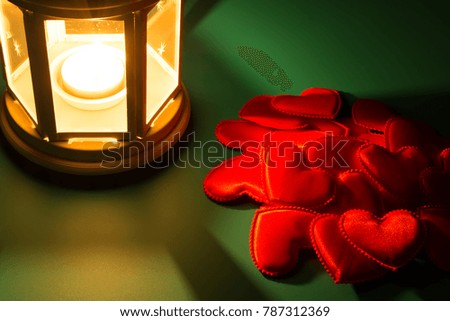 Lantern and small red hearts on dark green background.