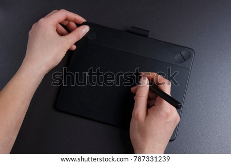 artist draws on graphic tablet. Design concept. Creative work. Hands of art on table with graphic tablet and pen