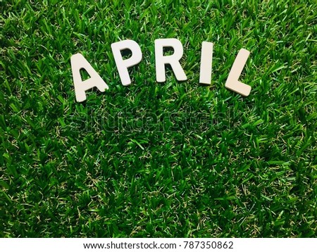 Image April, wooden alphabet April on green grass background with copy space for your text. Concept be used for calendar, month and background. Blur picture and exposure.