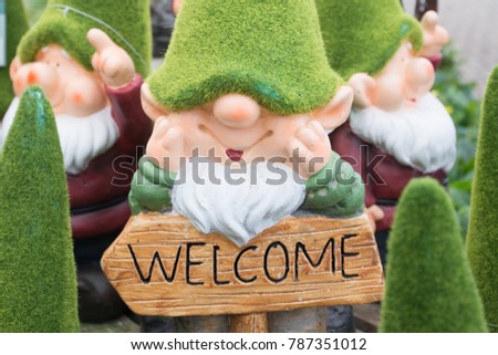 Garden gnome with grass hat and welcome sign