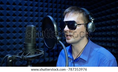 Blind Man in Black Glasses Reads Braille from the White Paper Sheet and Recording a Voice or Song in the Sound Recording Studio. Blind Man Speaks with His Voice Cartoon, Movie or Promotional Movie