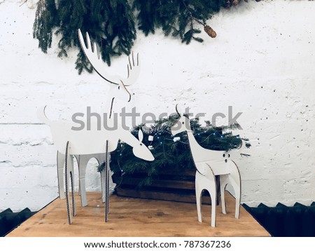 a family of deer cardboard animals. New Year's scenery. A branch of a fir-tree with cones is hanging on a white concrete wall. christmas decoration of the house. new Year. eco decor
