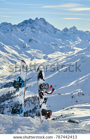 Two snowboard standing upright in snow between mountains on the background