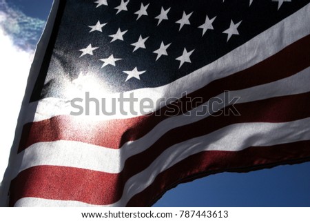 Close up of a United States Flag outside in the sun. Detail of the stars on blue background of the American flag waving in the wind. Looking at the sun through a US flag, noise/film grain filter added