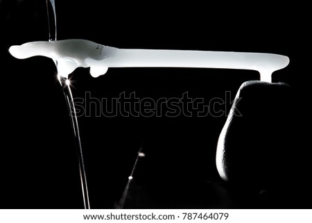Dripping wax on a wax stick on a plain black background