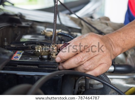 man hands holding screwdriver doing fix the brass battery terminal in car Royalty-Free Stock Photo #787464787