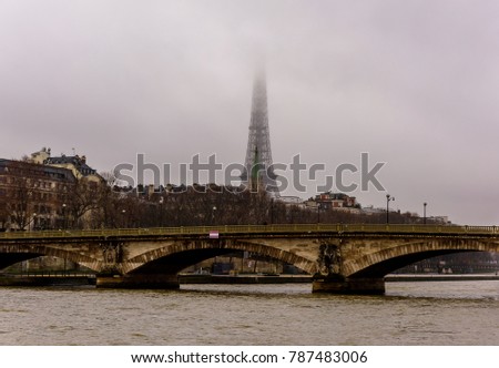 Foggy Paris morning panorama depicting Eiffel tower and bridge over Seine River.