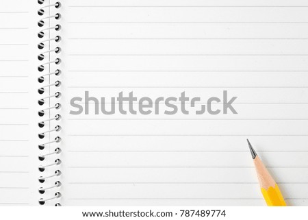 High resolution top view close up photo of wooden yellow pencil put on opened spiral binder lined notebook with copy space. Flash light made smooth shadow from yellow pencil and clear on lined paper.