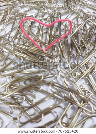 Valentine day concept - soft focus hand made heart-shaped red paper clip on silver paperclip background.