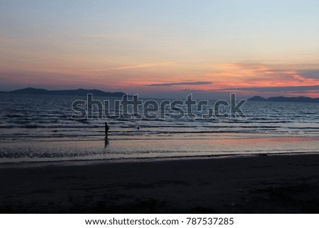 Sunset at beach and silhouette of person standing on beach, Thailand