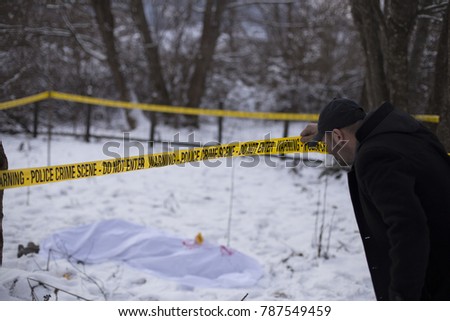 Investigator looking at body over the crime scene track. 