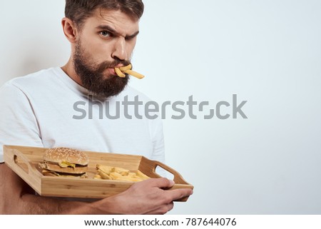 hungry man eating potatoes on a light background, fast food, hamburger                               