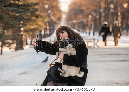 a girl in a dog's favorite pug walk in the park. The girl takes pictures of herself and the dog