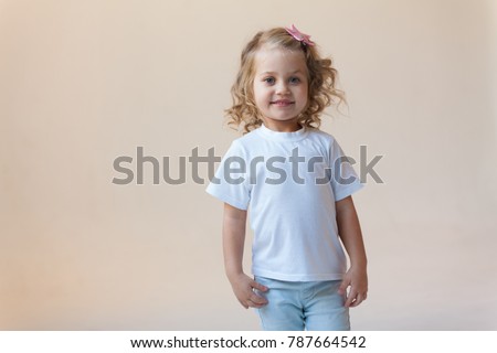 Cute little girl in a white t-shirt on a light background. Mock-up. Royalty-Free Stock Photo #787664542