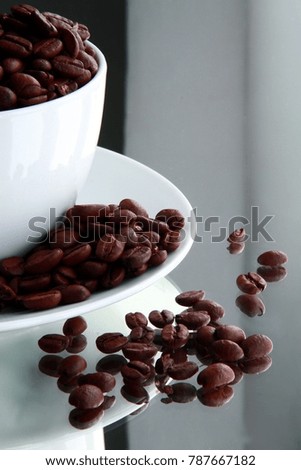 coffee beans in cup and saucer sitting on a table stock photo