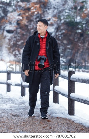 Asian young man taking pictures in winter snow field park Tourist.
