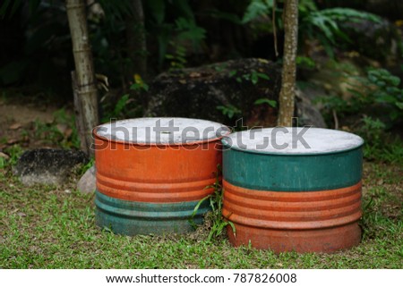 The two stool made from the metal barrel and cement put on the floor in the garden