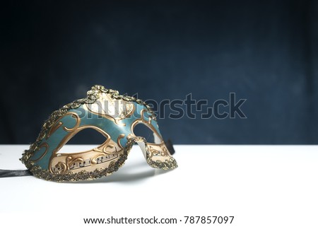 Blue venetian mask on white table with blue background and copy space