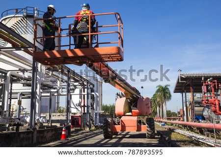 Two male  industry working at high in a boom lift  inspection of pipeline oil