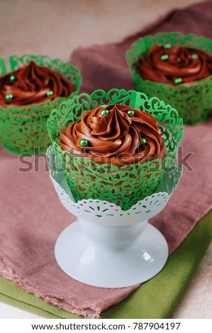 St. Patrick's Day party table: Chocolate cupcakes with green sugar sprinkles on beige background; selective focus
